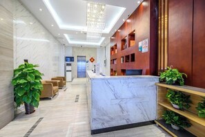 A hotel reception area with a marble reception desk, wooden shelving with plants, and a modern chandelier. - Derun Hotel Apartment (Guangzhou)