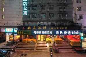 A building with multiple commercial units, including a brightly lit store with yellow bags and a sign with numbers 917 and 585. - Derun Hotel Apartment (Guangzhou)