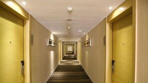 A hotel hallway with doors on both sides, a carpeted floor, and a ceiling with recessed lighting. - Derun Hotel Apartment (Guangzhou)