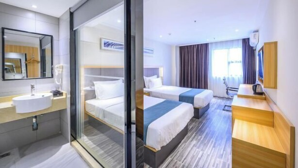 A hotel room with a glass partition, a bed, a bedside table, a desk, and a window with curtains. - Derun Hotel Apartment (Guangzhou)