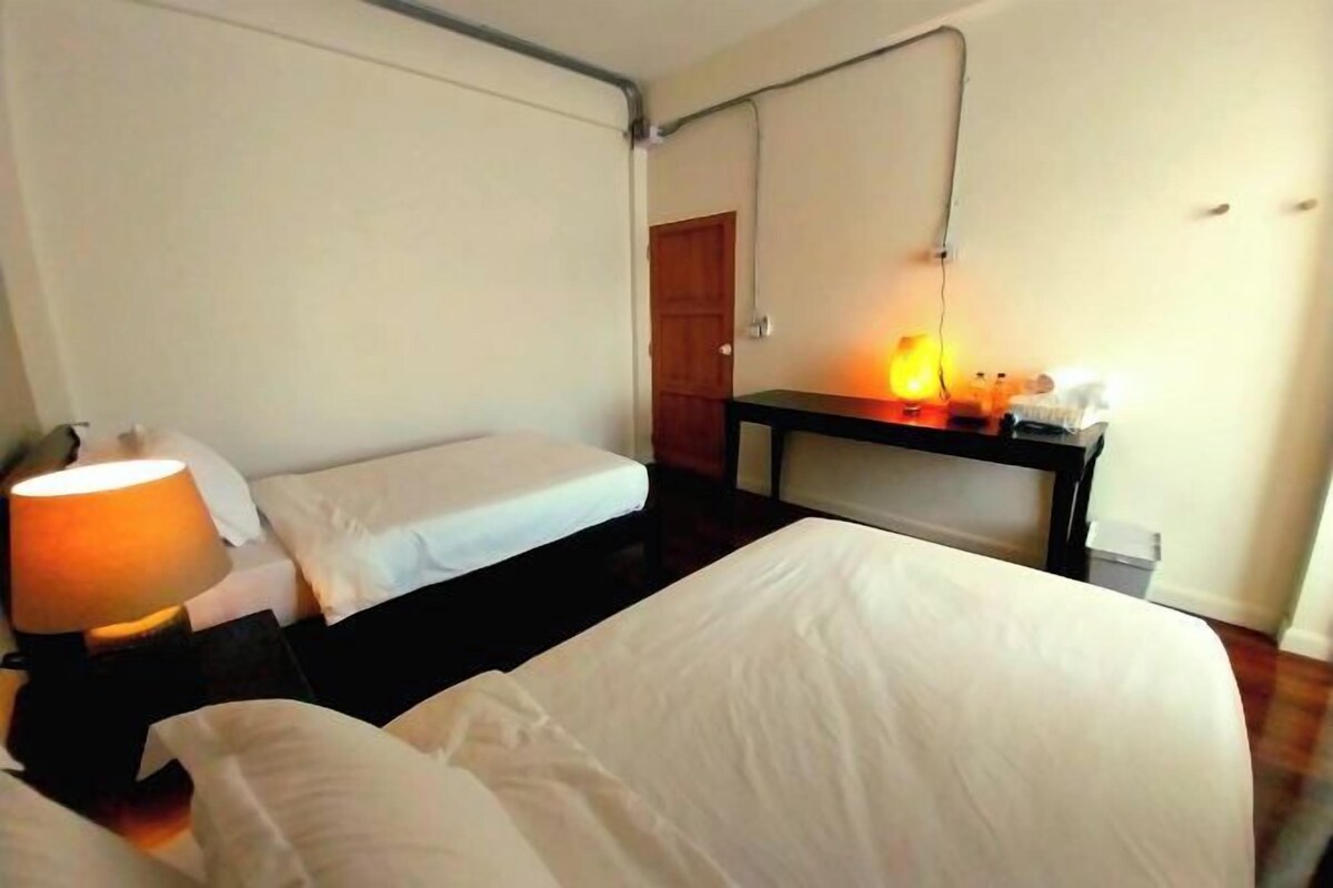 A hotel room with two beds, a desk, and a lamp.
