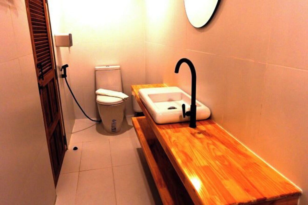 A compact bathroom with a toilet, a sink, and a wooden vanity.