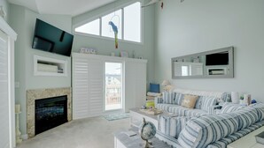 A living room with a fireplace, a sofa, a television, and a window with a view.