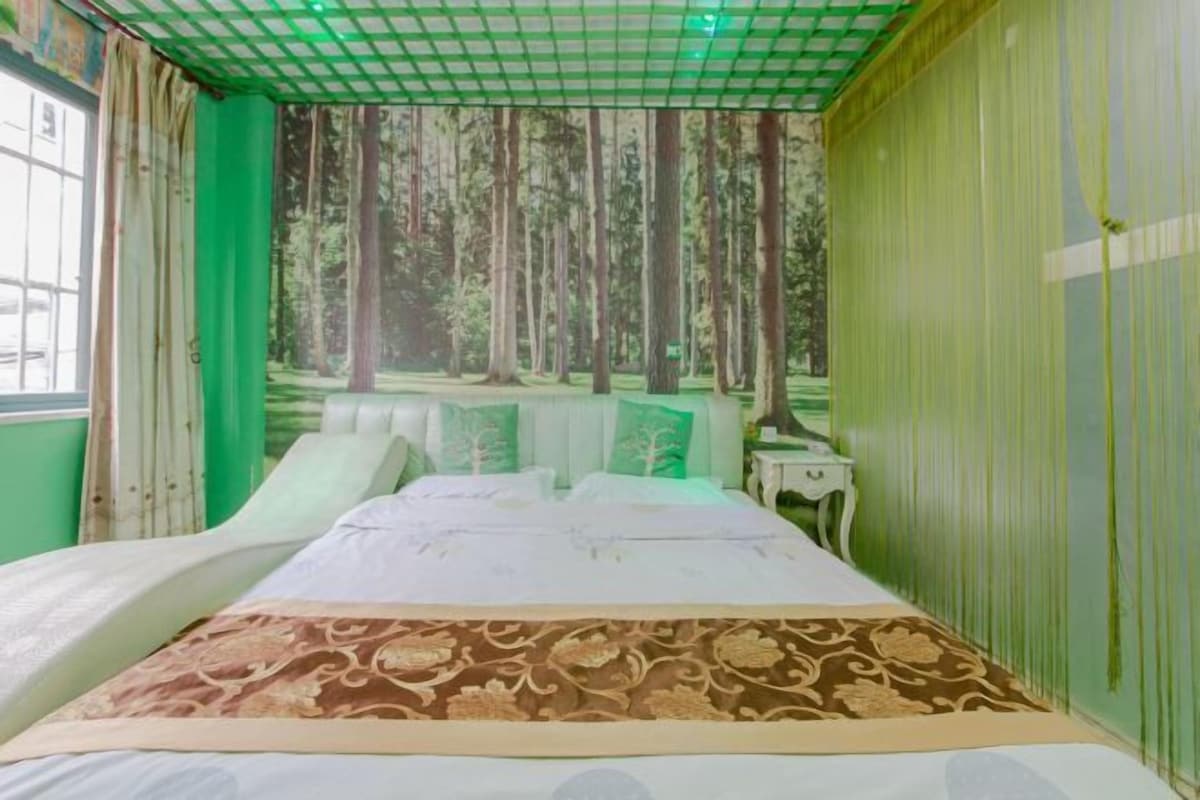 A room with a bed, a nightstand, and a view of a forest through the window.