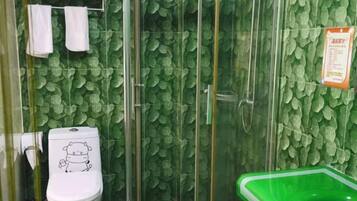 A bathroom with a toilet, shower, and green sink.