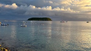 Paisaje costero con barcos y una pequeña isla a lo lejos.