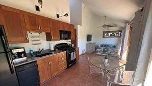 A modern kitchen with wooden cabinets, a stove, and a dining area with a glass table and chairs.
