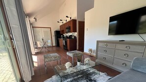 A living room with a sofa, ottoman, glass coffee table, and a TV.