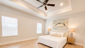 A bedroom with a large bed, two bedside tables, a ceiling fan, and two windows with blinds. - 4 BR/3BA (2K, Q, 2T) New Construction.  Pet friendly (Foley)