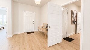 A hallway with wooden flooring, white doors, and a bench. - 4 BR/3BA (2K, Q, 2T) New Construction.  Pet friendly (Foley)