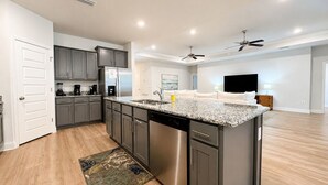 A modern kitchen with grey cabinets, a granite countertop, and a dishwasher. - 4 BR/3BA (2K, Q, 2T) New Construction.  Pet friendly (Foley)