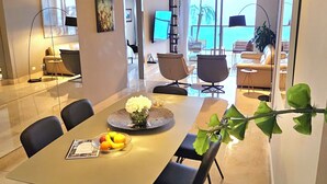 A modern dining area with a large table, black chairs, and hanging pendant lights.