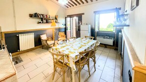 A dining area with a table set for four, wooden chairs, a radiator, a window with a view, and a bookshelf with books. - Apt 6 - Magical Grounds With Pool Jacuzzi Sleeps 4 (Spoleto)