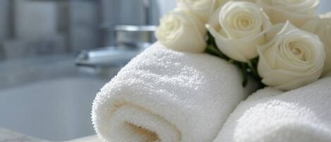 A bathroom with a white towel and a bouquet of white roses on a marble countertop.