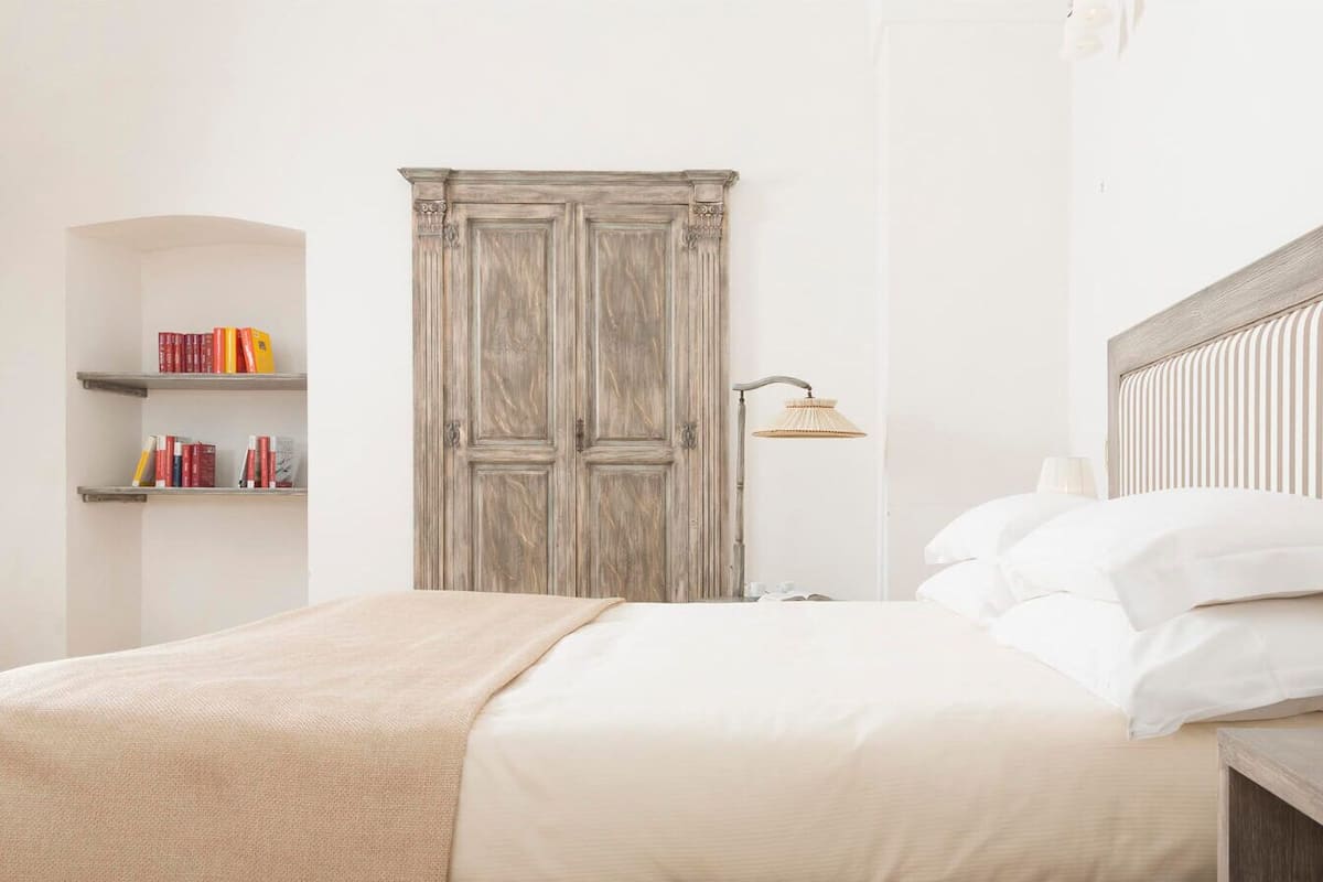 Un dormitorio ordenado con cama, mesita de noche, lámpara y armario.