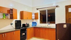 Una cocina compacta con armarios de madera, una estufa, un microondas y una ventana con cortina.