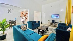 Una sala de estar moderna con un juego de sofá azul, una mesa de centro y un televisor en la pared.