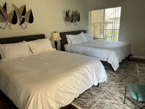 A hotel room with two beds, a patterned rug, and wall art.
