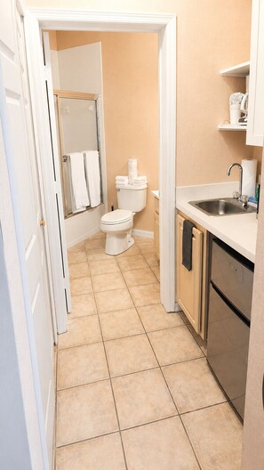 A compact bathroom with a toilet, a shower enclosure, and a sink with a stainless steel faucet.