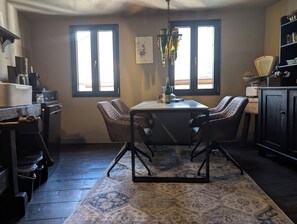 A kitchen with a dining table, chairs, a rug, and a chandelier.