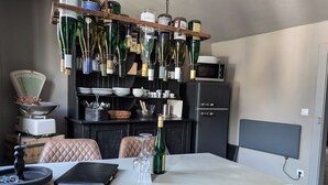 Un coin repas avec une table, des chaises, un meuble à bouteilles et un four à micro-ondes en arrière-plan.
