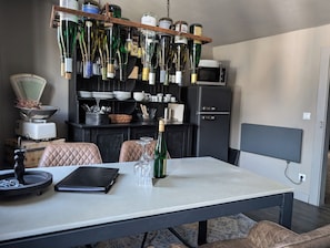A dining area with a table, chairs, a wine rack, and a microwave in the background.