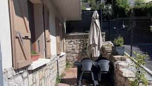 A patio area with stone walls, a table with chairs, and a potted plant.