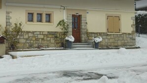A house with a stone facade, a wooden door, and a small porch with steps leading to the entrance.