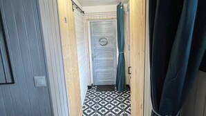 A narrow hallway with a patterned floor, wooden walls, and a door with a circular emblem.