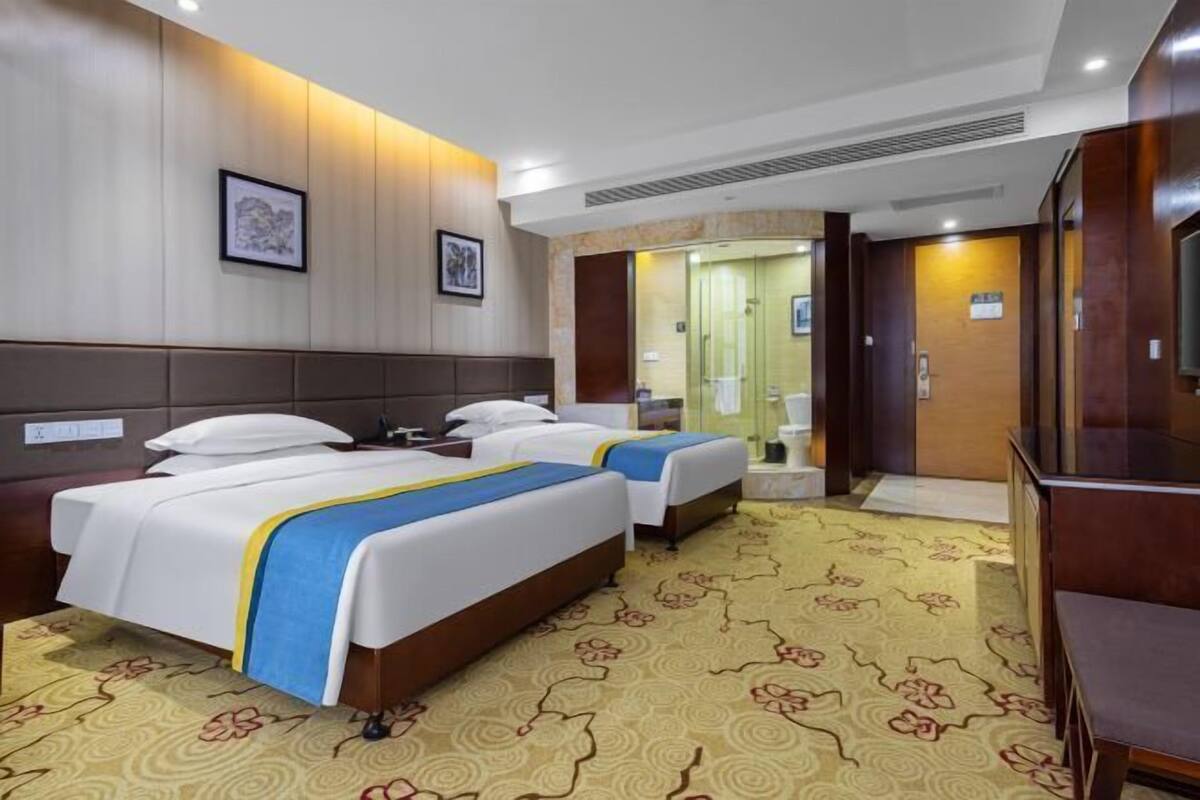 A hotel room with two beds, a large mirror, and a carpeted floor.