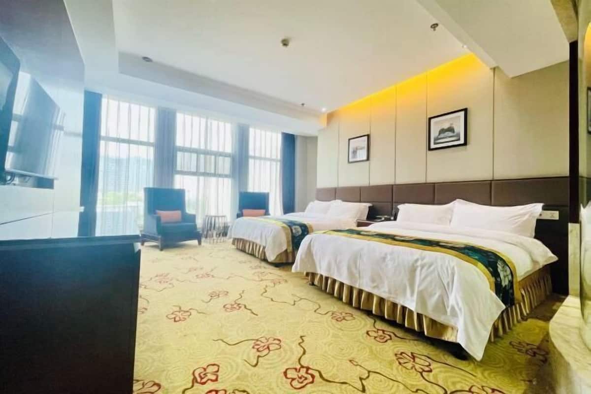 A hotel room with two beds, a TV, a desk, and a chair.