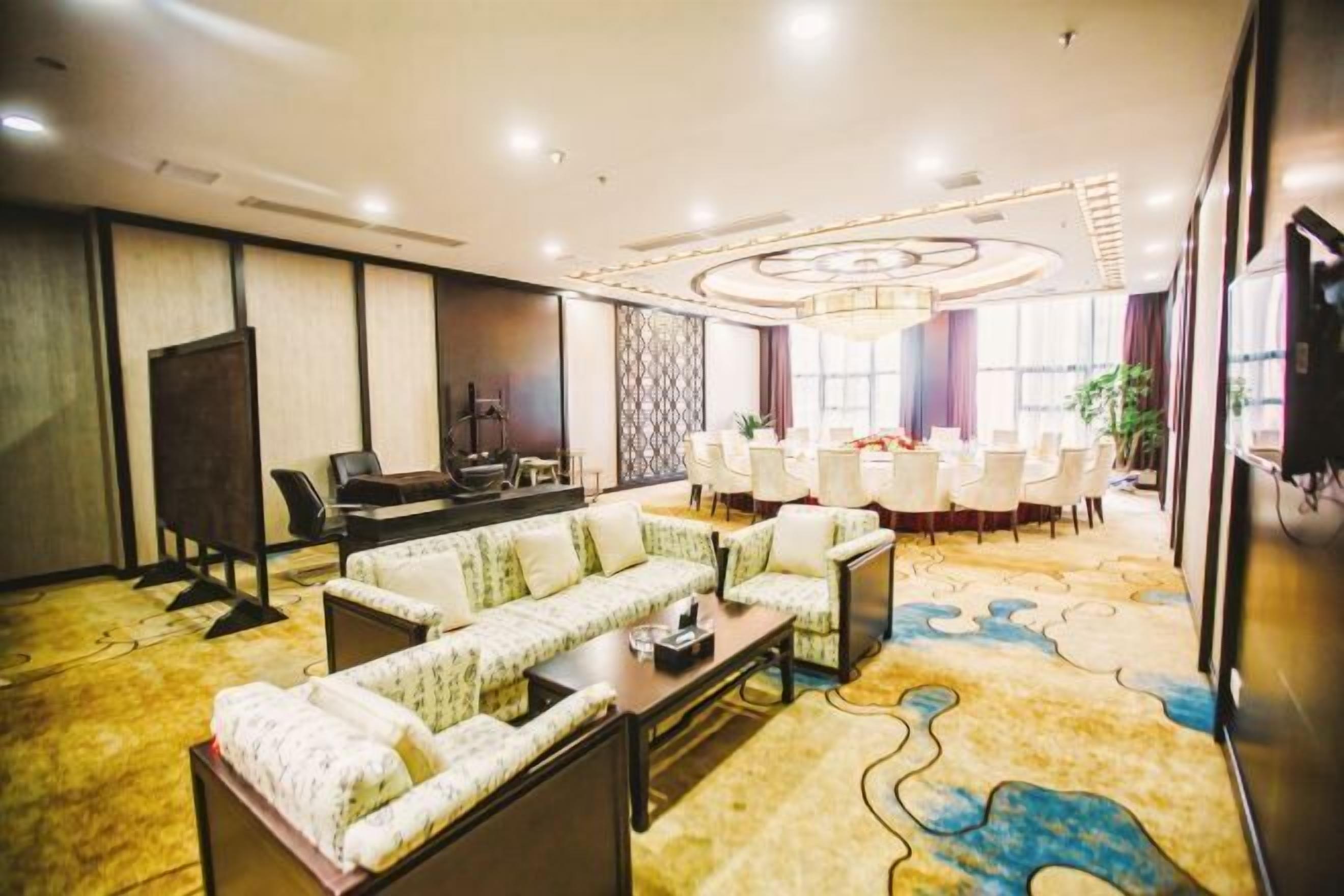 Un vestíbulo de hotel con una zona de estar, una mesa de conferencias y un ventanal grande.
