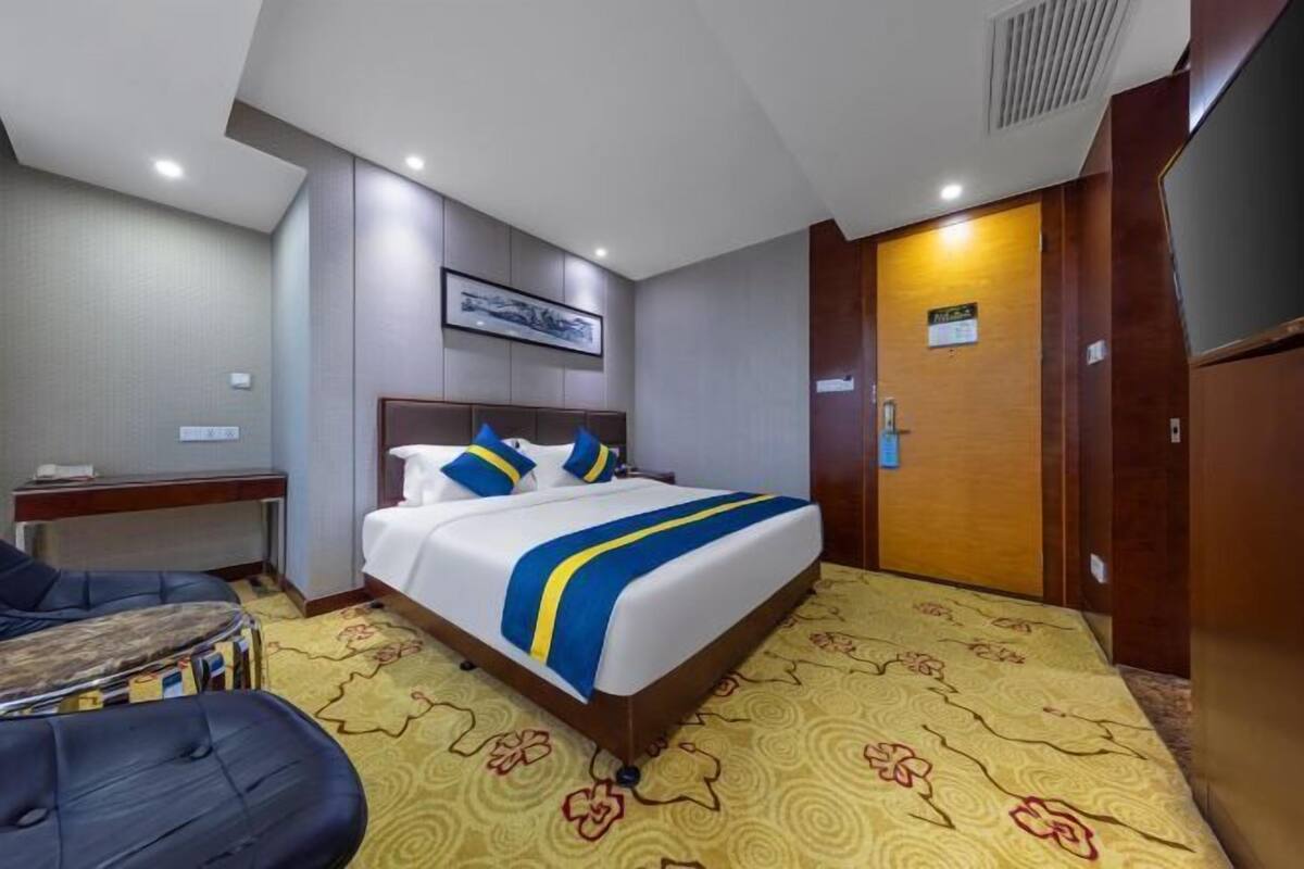 A hotel room with a bed, a desk, and a chair.