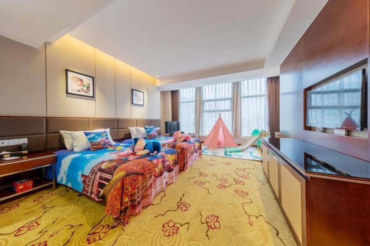 A hotel room with a large bed, a TV, and a window with curtains.