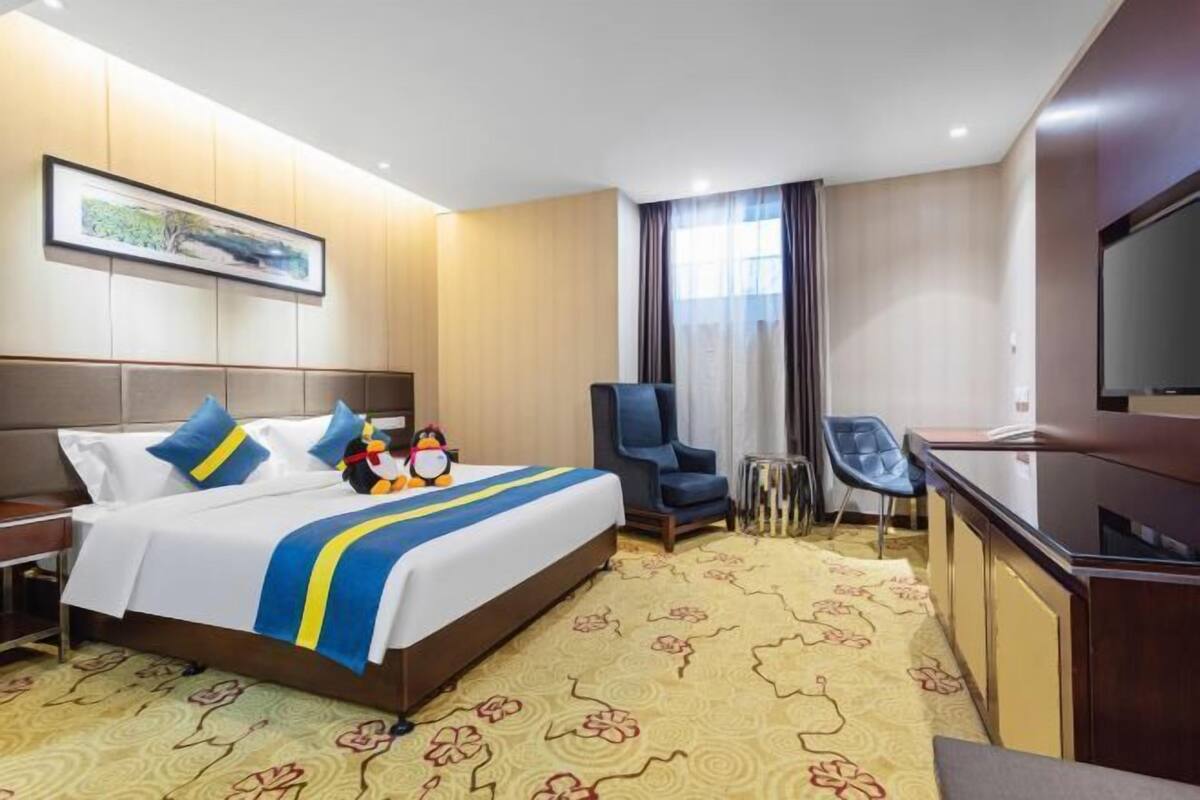 A hotel room with a bed, a desk, a chair, a television, and a framed picture on the wall.