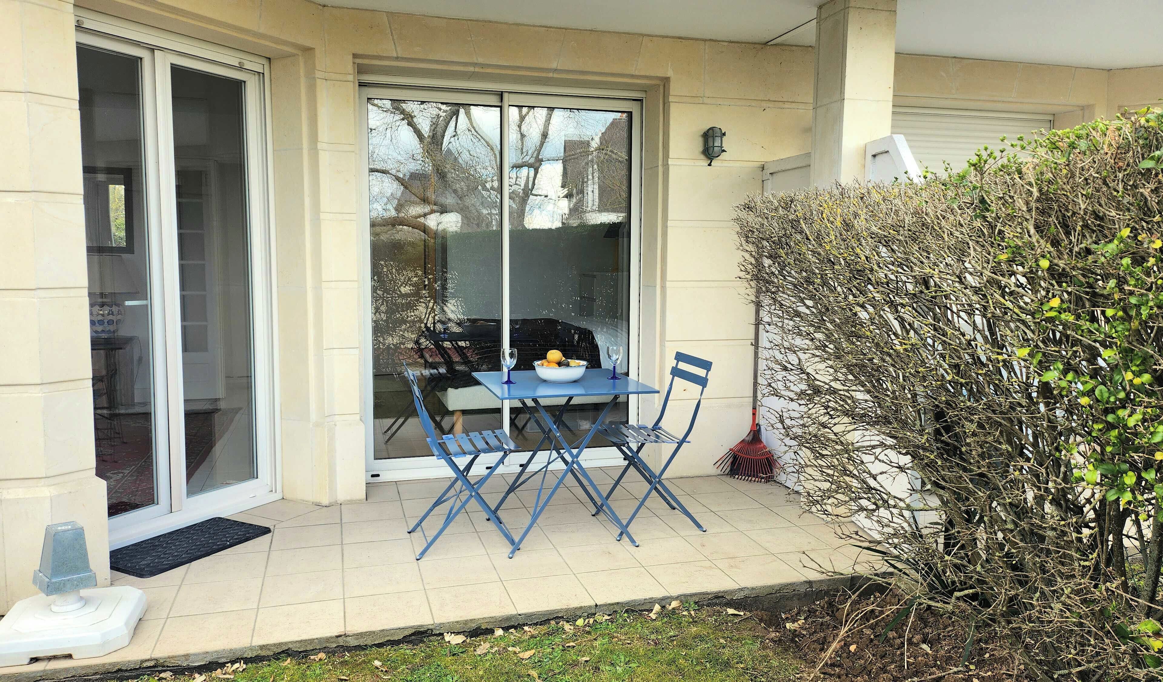 Une terrasse avec une table et des chaises, un saladier rempli de fruits et un balai.
