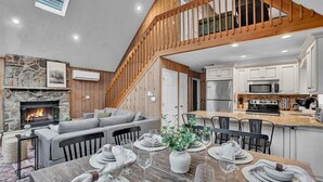 Ein großzügiger Wohnbereich mit Kamin aus Stein, einer Holztreppe und einer Küche mit modernen Geräten.