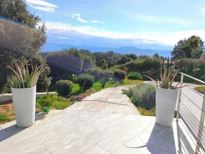 Un sentier qui mène à un belvédère offrant une vue panoramique, avec des plantes en pot de chaque côté.