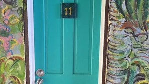 Une porte de couleur turquoise portant le numéro 11, encadrée d’une fresque colorée.