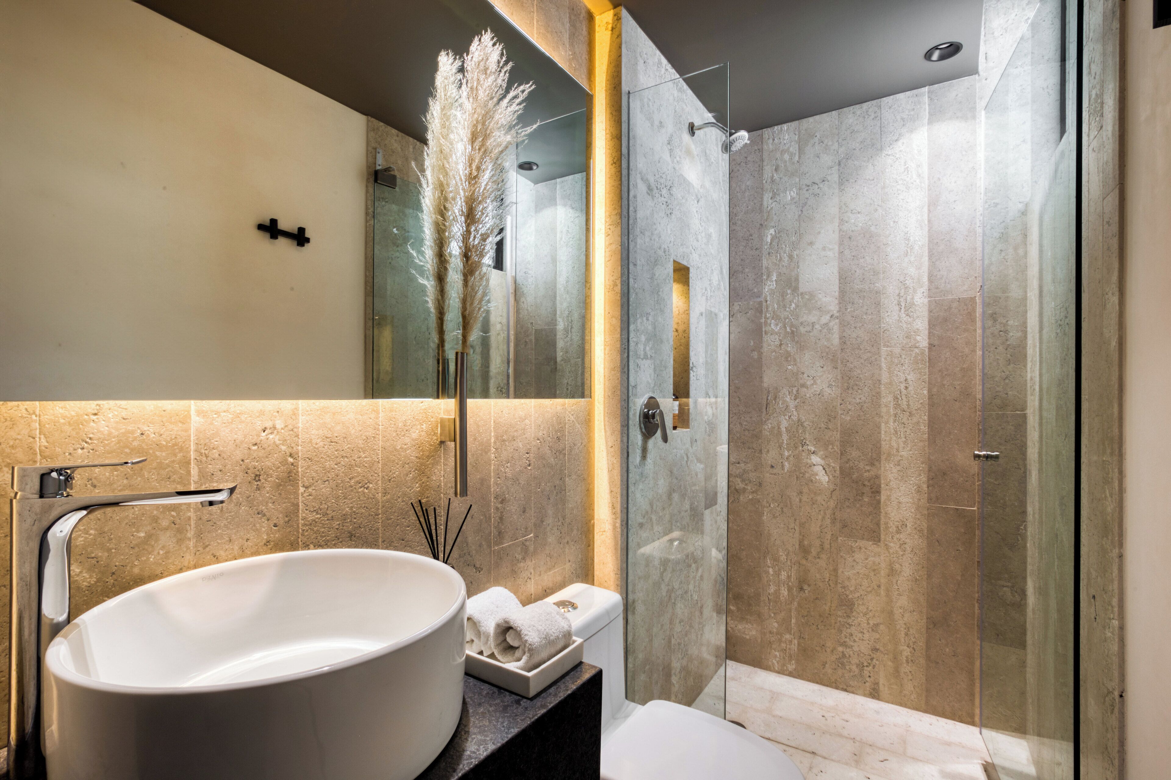A modern bathroom with a large white sink, a glass-enclosed shower, and a mirror above the sink.