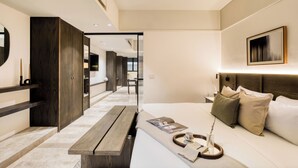 Una habitación de hotel moderna con una cama grande, un banco de madera, un escritorio y un espejo amplio.