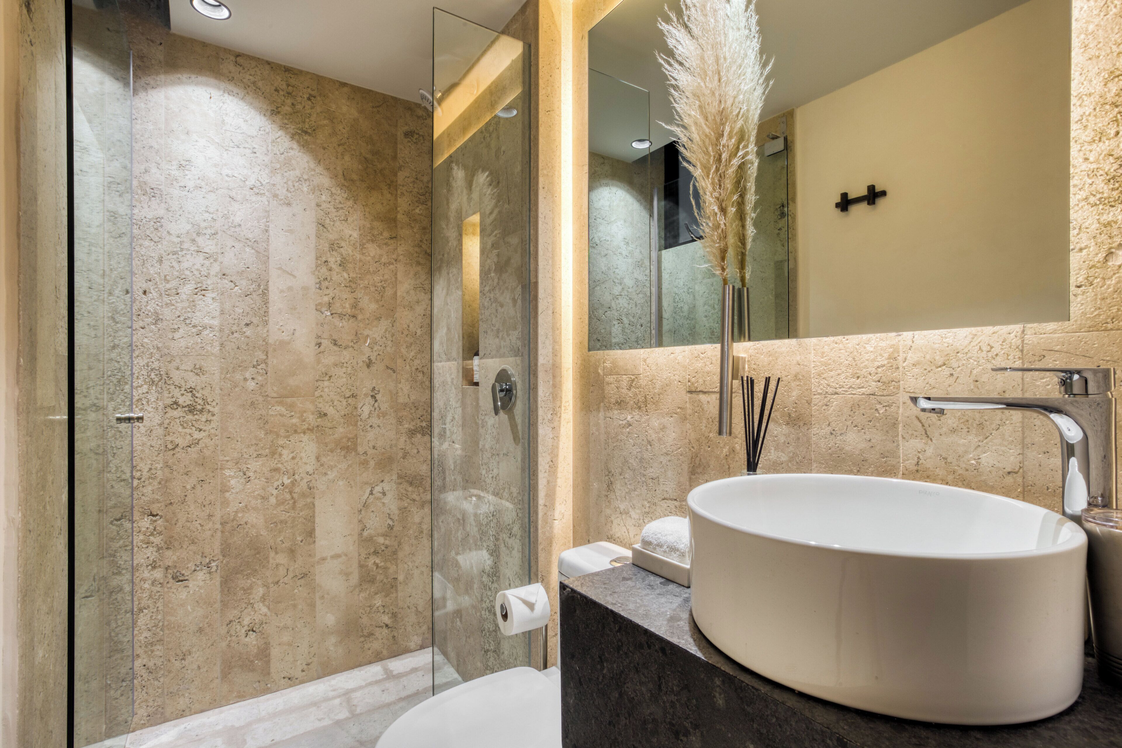 A modern bathroom with a glass-enclosed shower, a large oval sink, and a mirror above the sink.