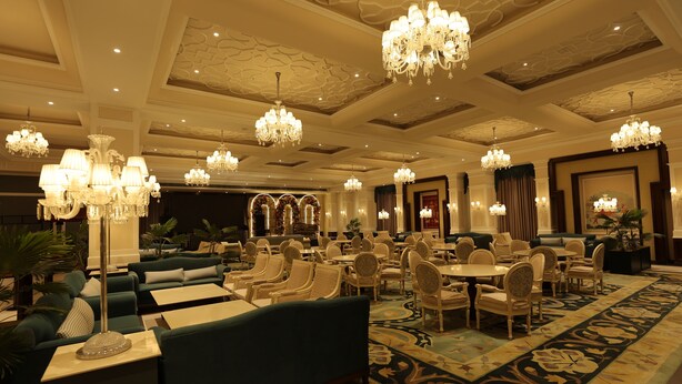 A spacious hotel lobby with multiple seating areas, chandeliers, and a patterned carpet. - The Lauriant Resorts (Patiala)