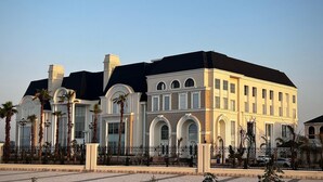 A large, multi-story building with a symmetrical facade, featuring arched windows and a central entrance. - The Lauriant Resorts (Patiala)