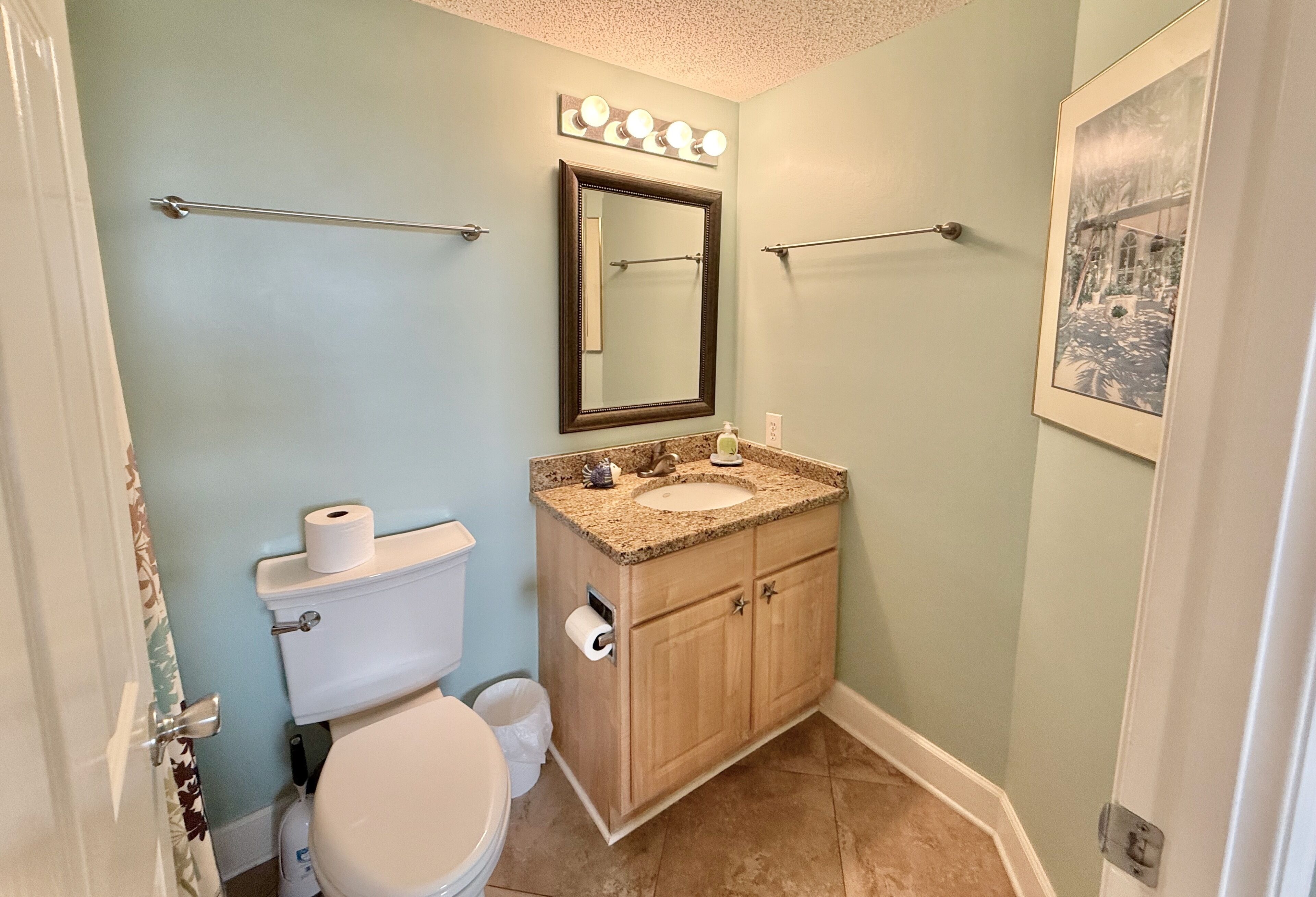 Un bagno con WC, lavandino, mobile lavabo e uno specchio con luci soprastanti.