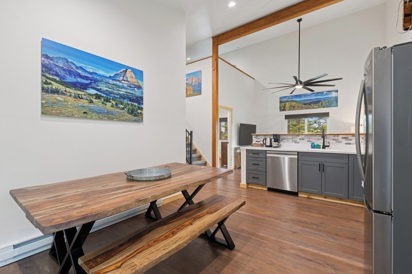 A modern kitchen with a wooden dining table, a built-in dishwasher, and a refrigerator.