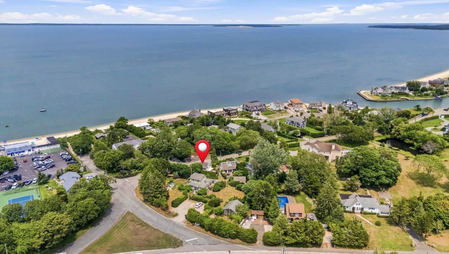 Ett bostadsområde vid kusten med hus, en strand och en småbåtshamn.