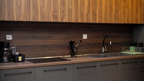 A kitchen with wooden cabinets, a stainless steel sink, and a coffee maker. - Dioroh Suites Meteora 303 (Kalabaka)