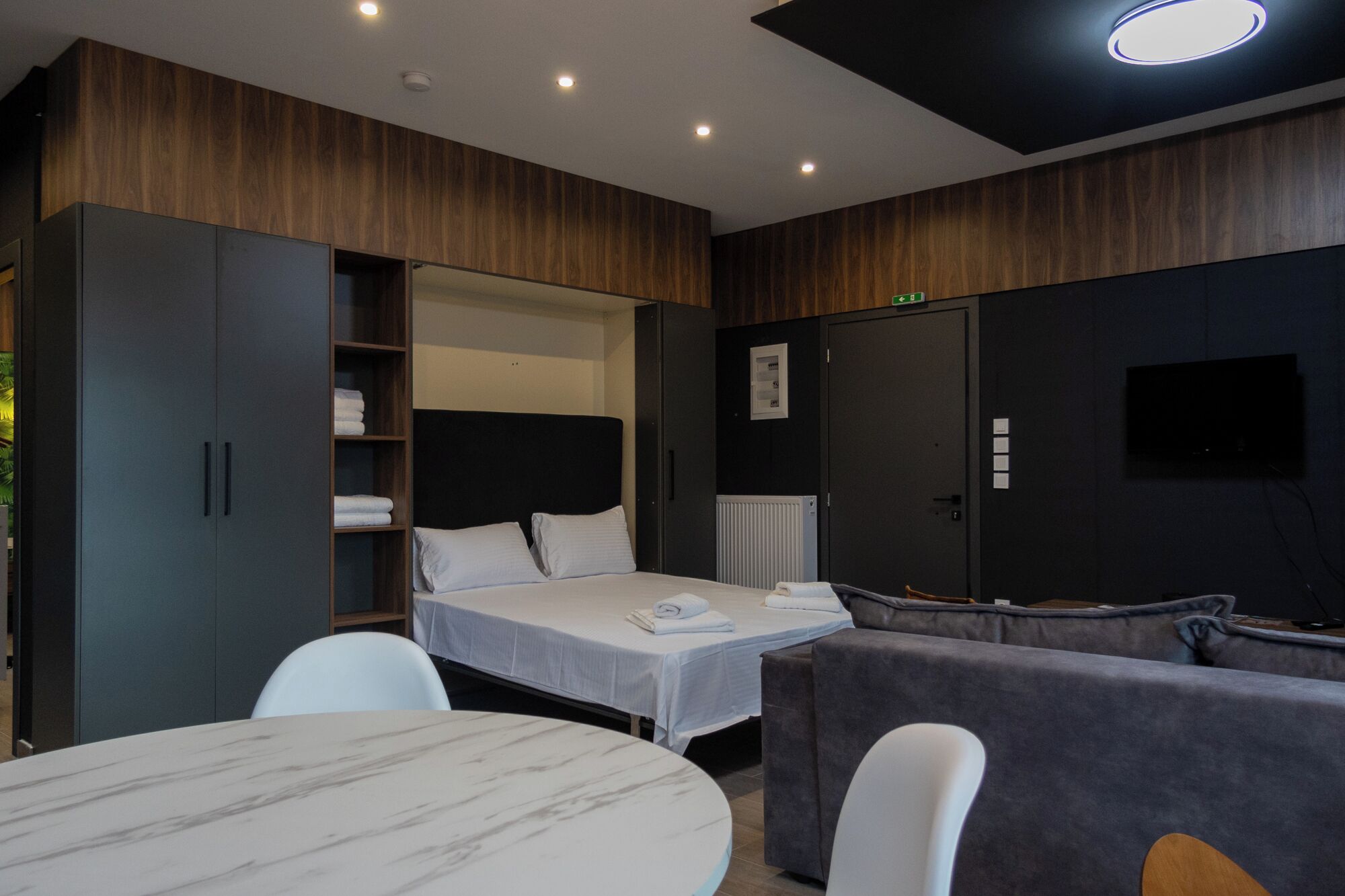 Una habitación de hotel moderna con una cama, un sofá, una mesa y un televisor.