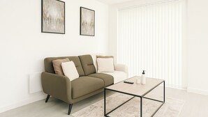 Een moderne woonkamer met een bank, een salontafel en twee kunstwerken in lijsten aan de muur.